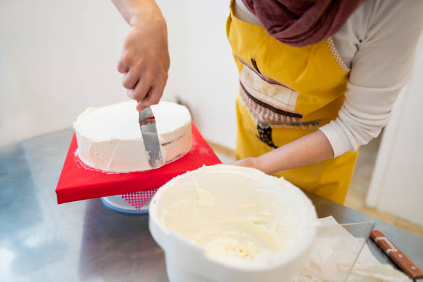 istock Close up of woman In bakery decorating cake with icing 1154651433