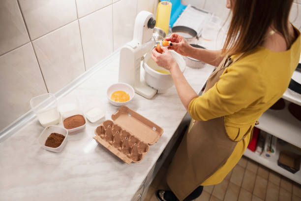 istock Adult woman cracking eggs at a kitchen counter 1154651460