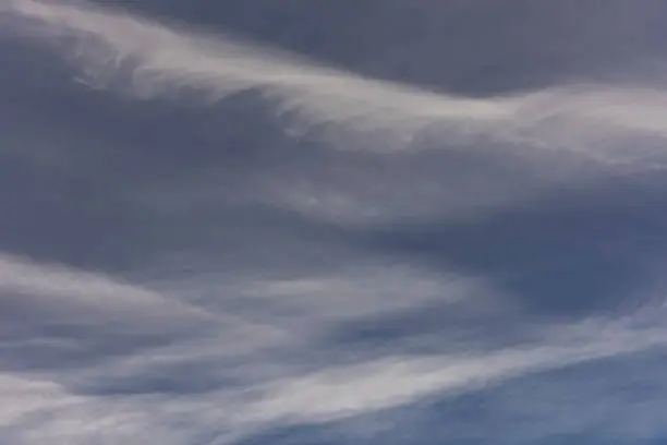 Photo of Strands of wispy cirrocumulus clouds zig-zagging across a pale blue sky.