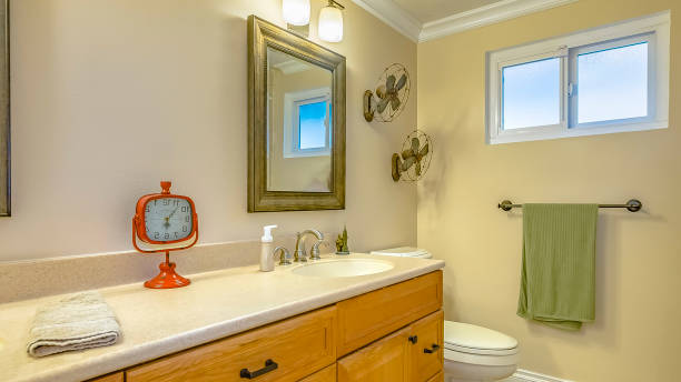 istock Panorama Double vanity with wooden cabinets inside a bathroom with small window 1154664387