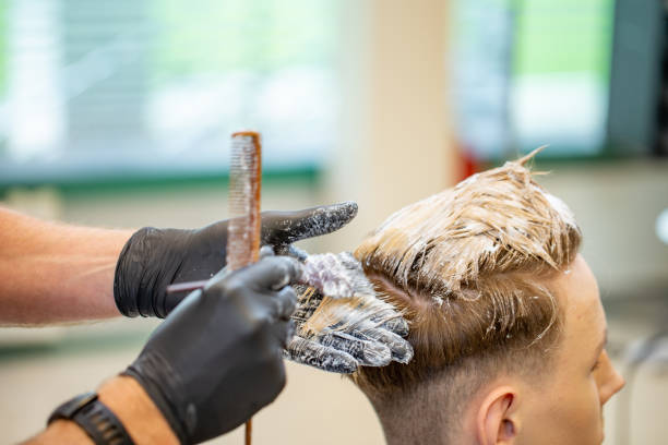 Hairdresser Bleaching Hair of a Young Adult Man Hairdresser Bleaching Hair of a Young Adult Man. casarsaguru stock pictures, royalty-free photos & images