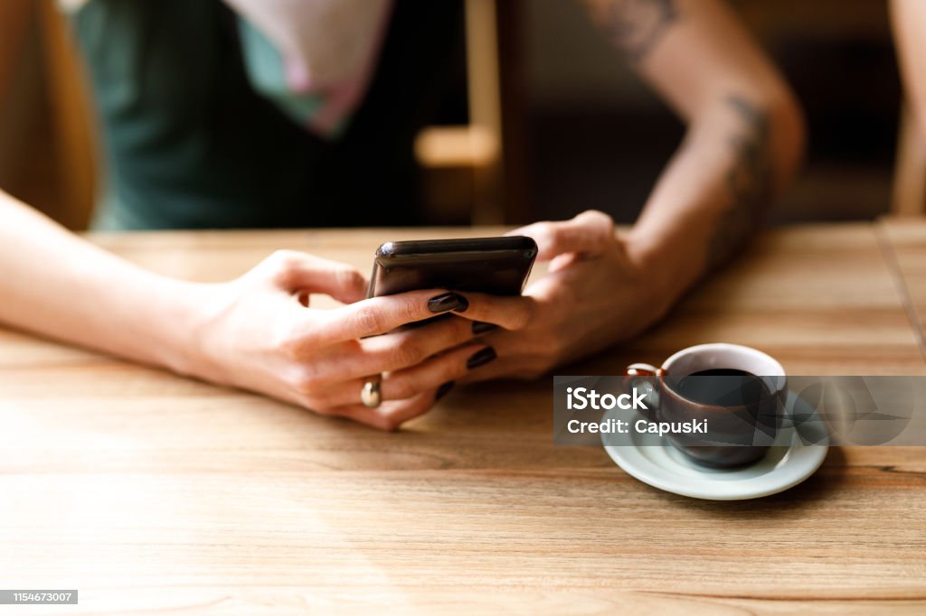 Young woman using phone at cafe table Young woman using phone at cafe table. Convenience Stock Photo