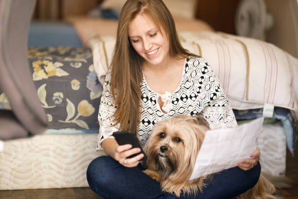 istock Woman paying bills with her cell phone with her dog 1154673066