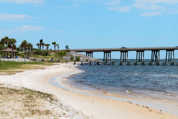 navarre park coast beach, people walking on wharf pier boardwalk by ocean water with pensacola bay bridge, gulf of mexico, florida panhandle in emerald coast - highway 94 imagens e fotografias de stock