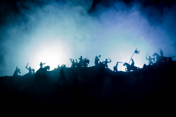 istock Medieval battle scene with cavalry and infantry. Silhouettes of figures as separate objects, fight between warriors on dark toned foggy background with medieval castle. 1154686472