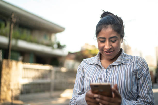 istock Latin woman using smartphone while walking in the street 1154686611