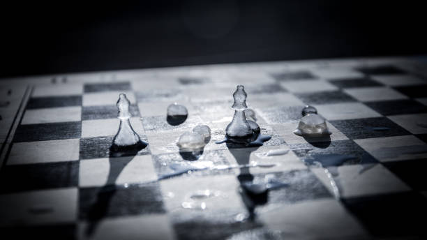 Strategy and tactics concept. Icy frosted chess figures standing on a chessboard during sunset. Melting ice chess