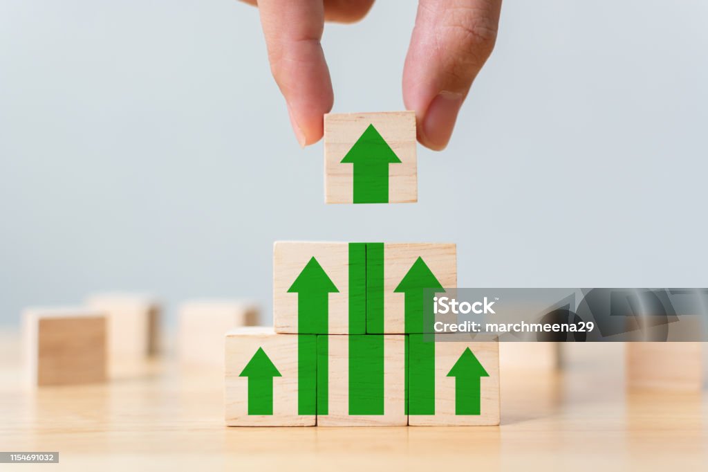 Ladder career path for business growth success process concept. Wood block stacking as step stair with arrow up. Hand putting wooden cube block on top pyramid Growth Stock Photo
