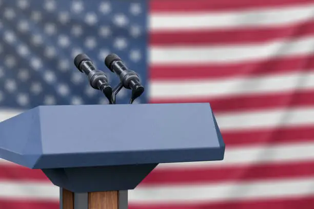 Podium lectern with two microphones and United States flag in background