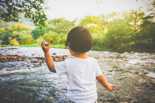 Two boys enjoying throwing rocks at riverbank