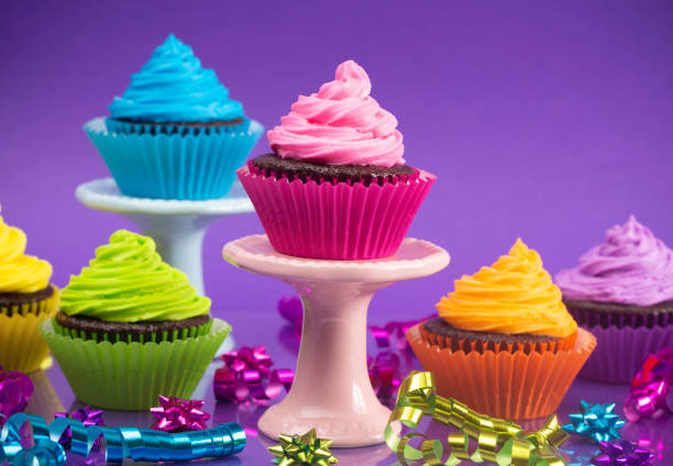 Rainbow Colored Frosted Chocolate Cupcakes with Confetti and Bows Set for a Party