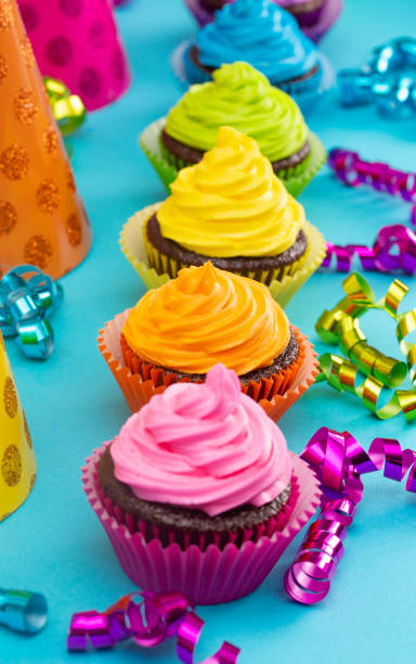 regenbogen gefärbte schokolade cupcakes auf einem teal-hintergrund - cupcake chocolate pink polka dot stock-fotos und bilder