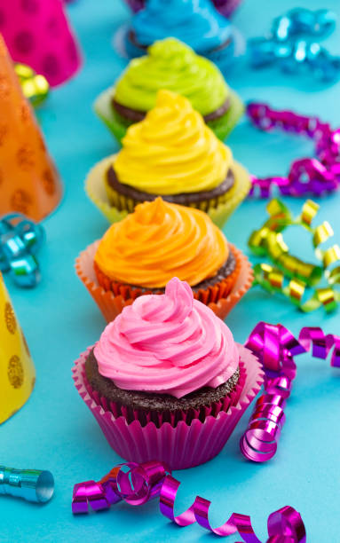 regenbogen gefärbte schokolade cupcakes auf einem teal-hintergrund - cupcake chocolate pink polka dot stock-fotos und bilder