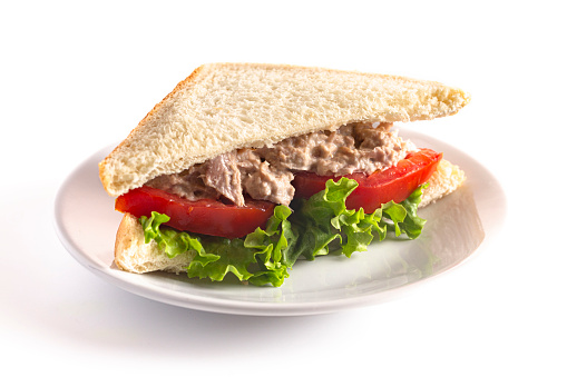 Un sándwich de ensalada de atún con tomate y lechuga aislada sobre un fondo blanco 