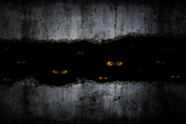 Photo of Scary eyes in damaged grungy crack and broken concrete wall and the dark