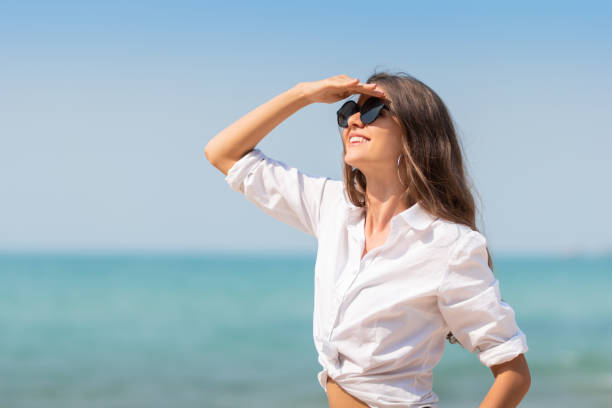 woman in sunglasses is smiling over blue sky.