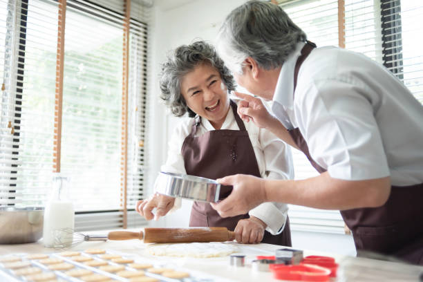 istock Happy Asian senior couple in brown aprons having fun. 1154704826