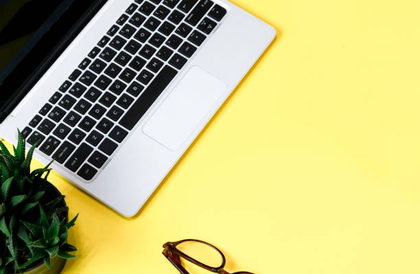 istock Laptop placed on a yellow table background of business working place with cup coffee, Empty workspace 1154705086