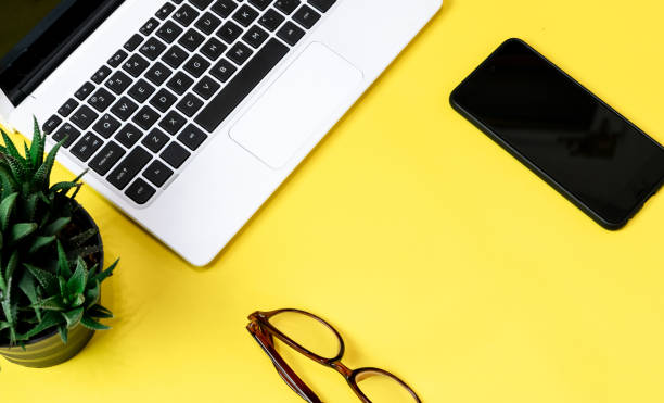 istock Laptop placed on a yellow table background of business working place with cup coffee, Empty workspace 1154705088