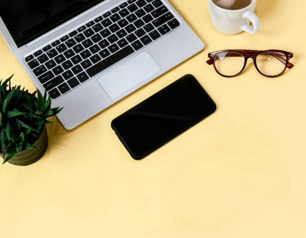 istock Laptop placed on a yellow table background of business working place with cup coffee, Empty workspace 1154705105