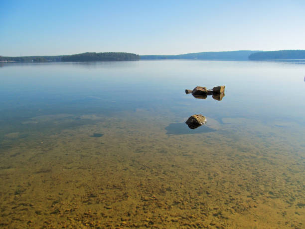 Summer idyllic landscape with beautiful lake. Calm transparent water surface with stones and sandy bottom on a bright quiet day. Harmony and pacification of nature - a beautiful concept for wallpaper. Lake Elovoe, Ural, Russia. shallow stock pictures, royalty-free photos & images