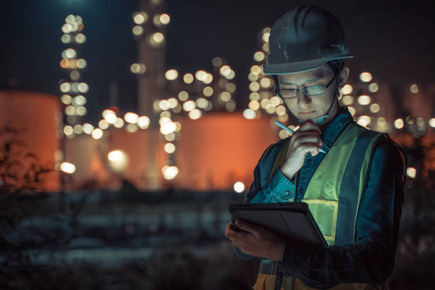 engenheiro petroquímico homem asiático trabalhar tarde e duro com tablet inteligente dentro da refinaria de petróleo e gás fábrica da indústria à noite - pipeline gas pipe pipe natural gas - fotografias e filmes do acervo