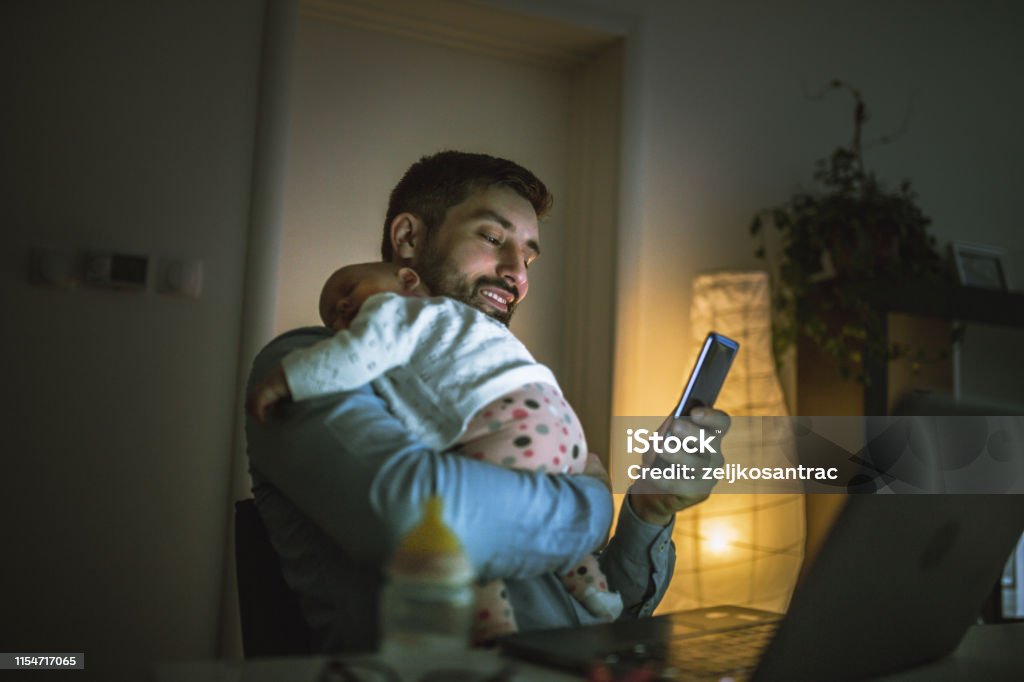 Young father working at home with his baby  girl Night Stock Photo