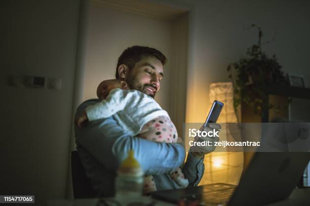 Young Father Working At Home With His Baby Girl Stock Photo - Download Image Now - Night, Telephone, Using Phone