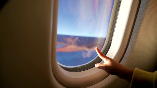 Child hand pointing on thw airplane window.