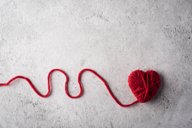 istock Red yarn heart shaped on the wall background 1154719586
