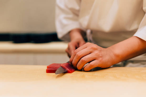 Japanese Omakase Chef cut bluefin tuna (Otoro in Japanese) neatly by knife on wooden kitchen counter for making sushi. Japanese Omakase Chef cut bluefin tuna (Otoro in Japanese) neatly by knife on wooden kitchen counter for making sushi. japanese chef stock pictures, royalty-free photos & images