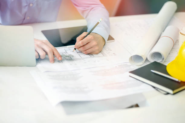 istock Young engineer or architect,working with blueprint and laptop in his office. 1154722264