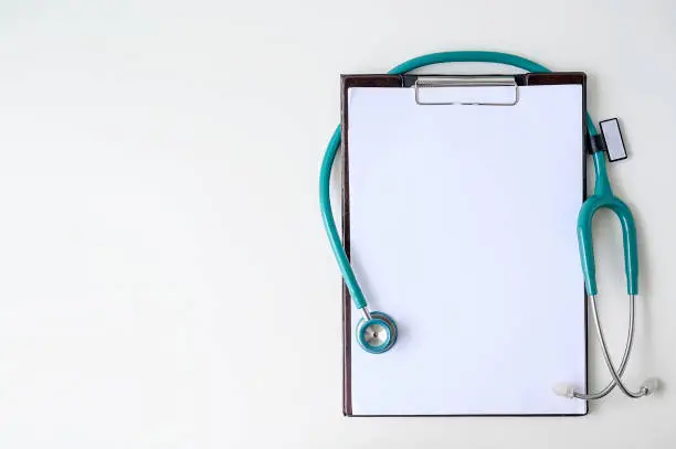 Photo of Blank medical clipboard with stethoscope on white background.