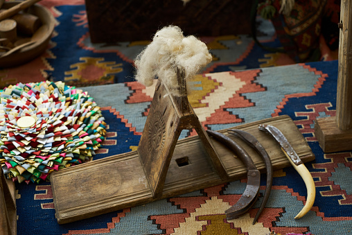 Old wooden cotton spindle with a ball of wool thread for the manufacture of woolen threads on a tissue background