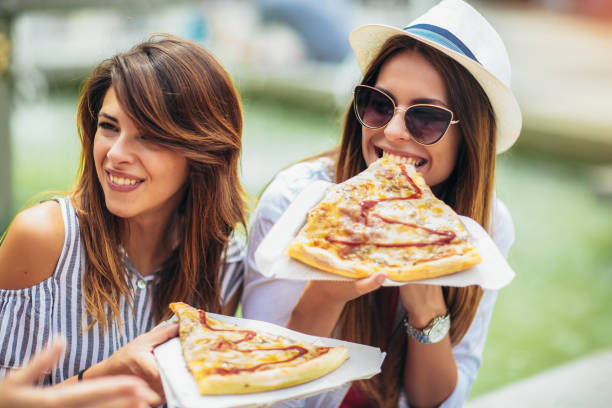 istock Three beautiful young women eating pizza after shopping, having fun together. 1154724005