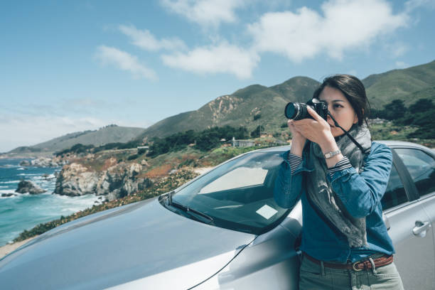 istock Woman standing outside car holding camera 1154724808