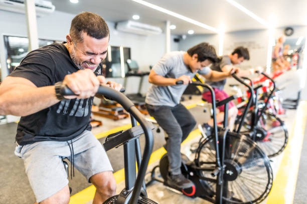 istock Three asian men exercising on airbikes in modern gym 1154725652