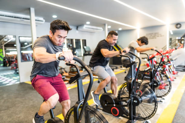 istock Three asian men exercising on airbikes in modern gym 1154725982