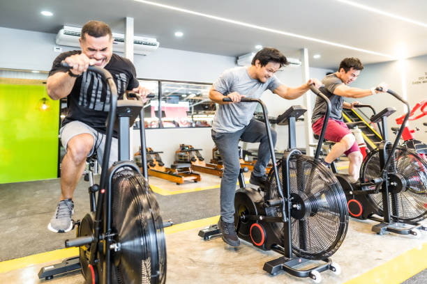 istock Three asian men exercising on airbikes in modern gym 1154727083