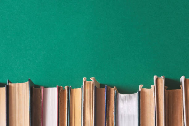 alte bücher auf bücherregalen mit grünem hintergrund - book book spine in a row library stock-fotos und bilder