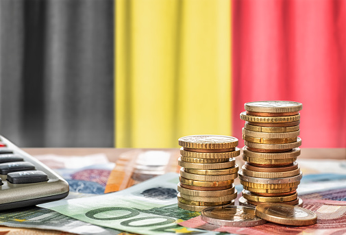 Billetes y monedas en euros frente a la bandera nacional de Bélgica photo