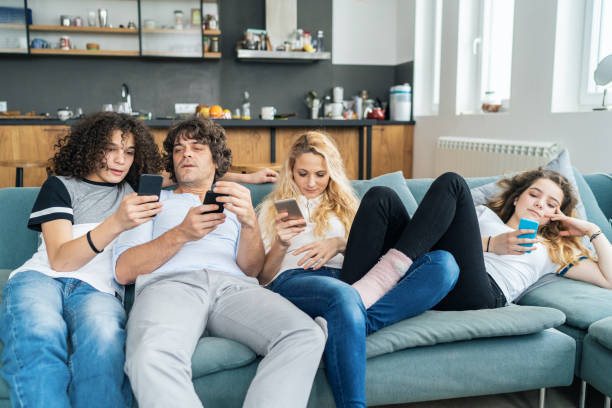 Relaxing at home with wireless technology Family with teenage children Relaxing at home with smartphones family dependency mother family with two children stock pictures, royalty-free photos & images