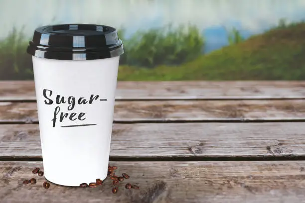 Sugarfree coffee to-go cup on a rustic wooden table. Nature background and wallpaper. Easy to customize.