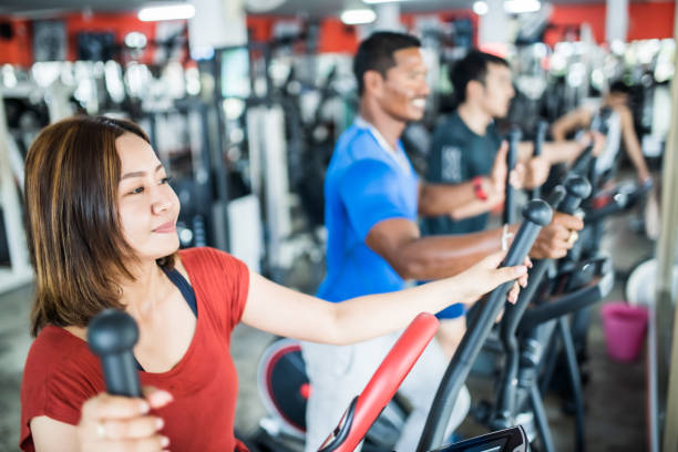 istock Three people exercising on cross trainer in the gym 1154736500