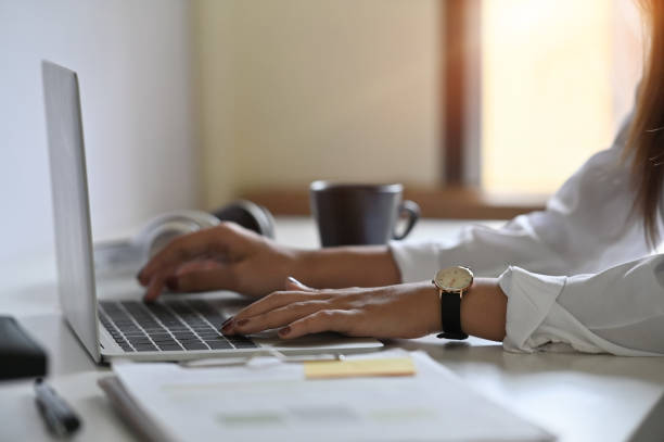 istock Woman using laptop computer on table with cropped shot photo. 1154745073