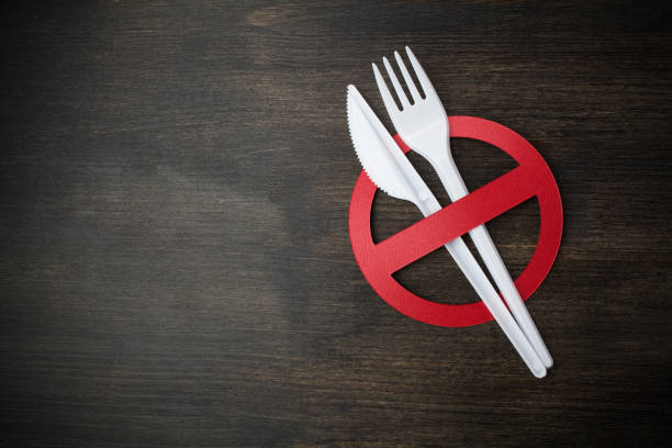 istock White plastic tableware on a wooden background as a symbol of environmental pollution. Ban single use plastic. 1154746670