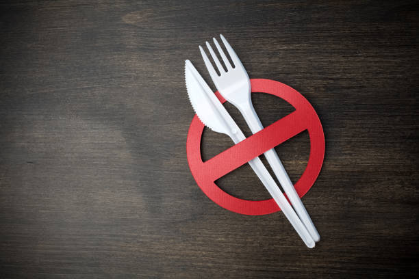istock White plastic tableware on a wooden background as a symbol of environmental pollution. Ban single use plastic. 1154747104