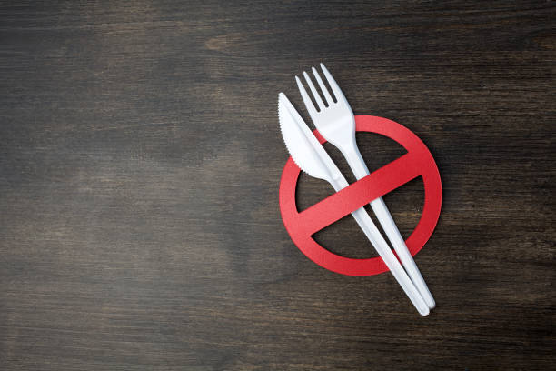 istock White plastic tableware on a wooden background as a symbol of environmental pollution. Ban single use plastic. 1154748400