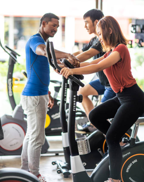 istock Personal trainer coaching two people on bycicle in the gym 1154755102