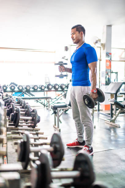 istock Three asian men exercising with dumbbells in modern gym 1154756883